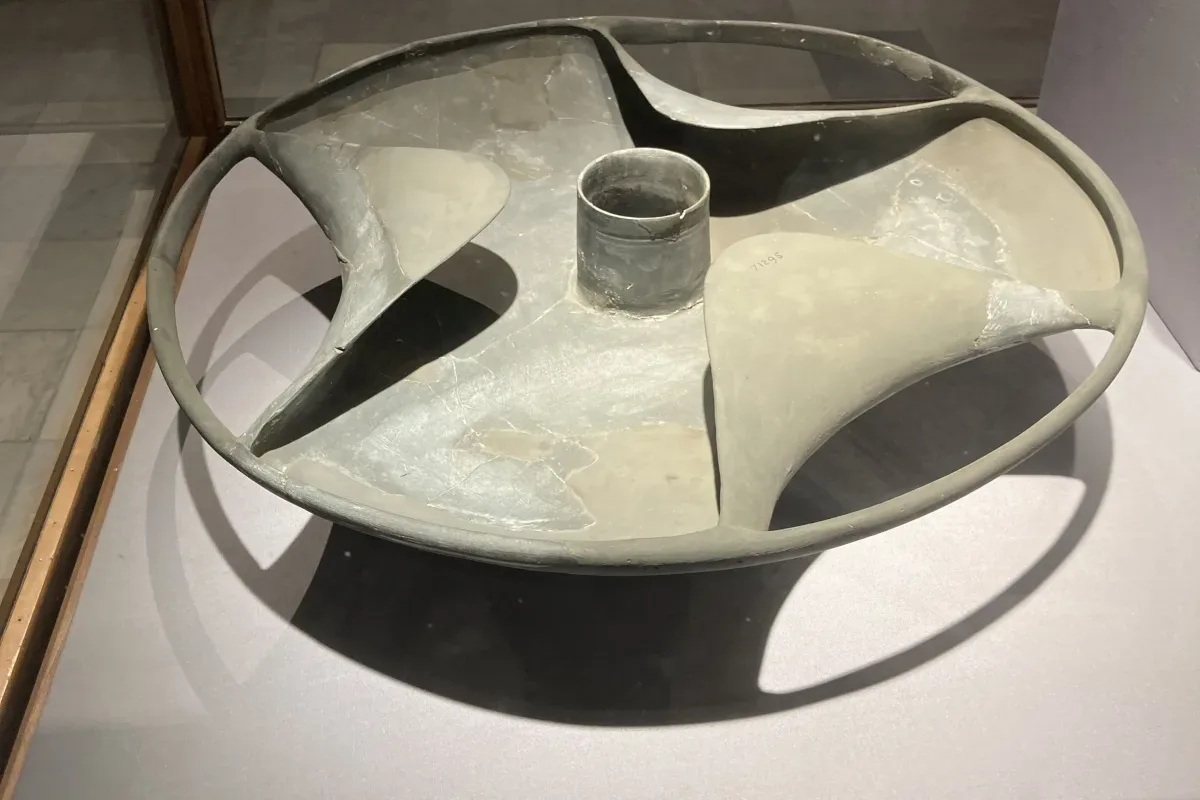 The Sabu disk displayed in a glass case at the Egyptian Museum in Cairo, its three curved blades and central opening resting on a stand