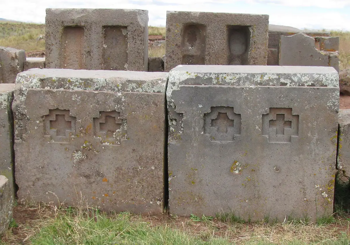 Upright monolithic andesite blocks at Puma Punku decorated with precise reliefs of the Andean cross, featuring sharp internal corners and flat surfaces